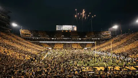 Packed stadium at night with fireworks over the field