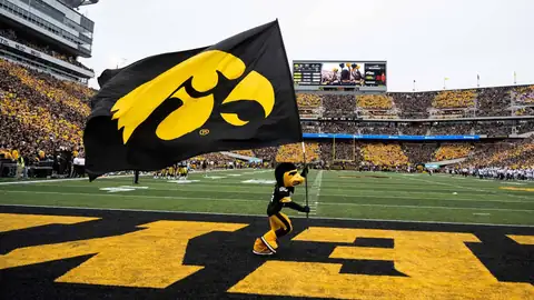 Herky the Hawk mascot running with a Tigerhawk flag across the end zone
