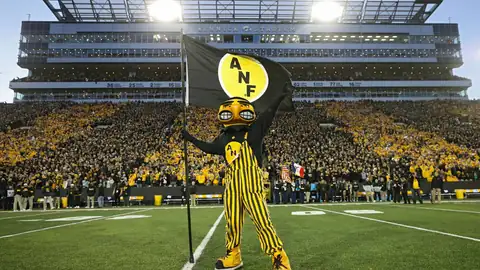 Herky the Hawk mascot holding a flag in front of a full stadium
