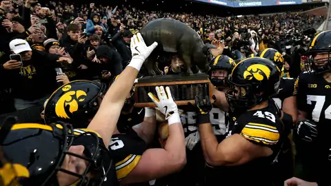 Iowa football players lifting a trophy after a win